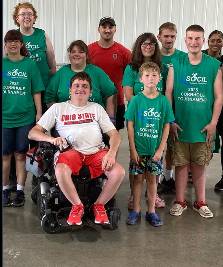 A group of SOCIL participants wearing green 2025 Cornhole Tournament shirts, smiling together at the event.