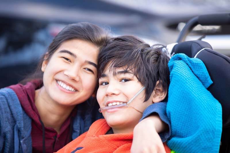 A brother and sister smiling and hugging