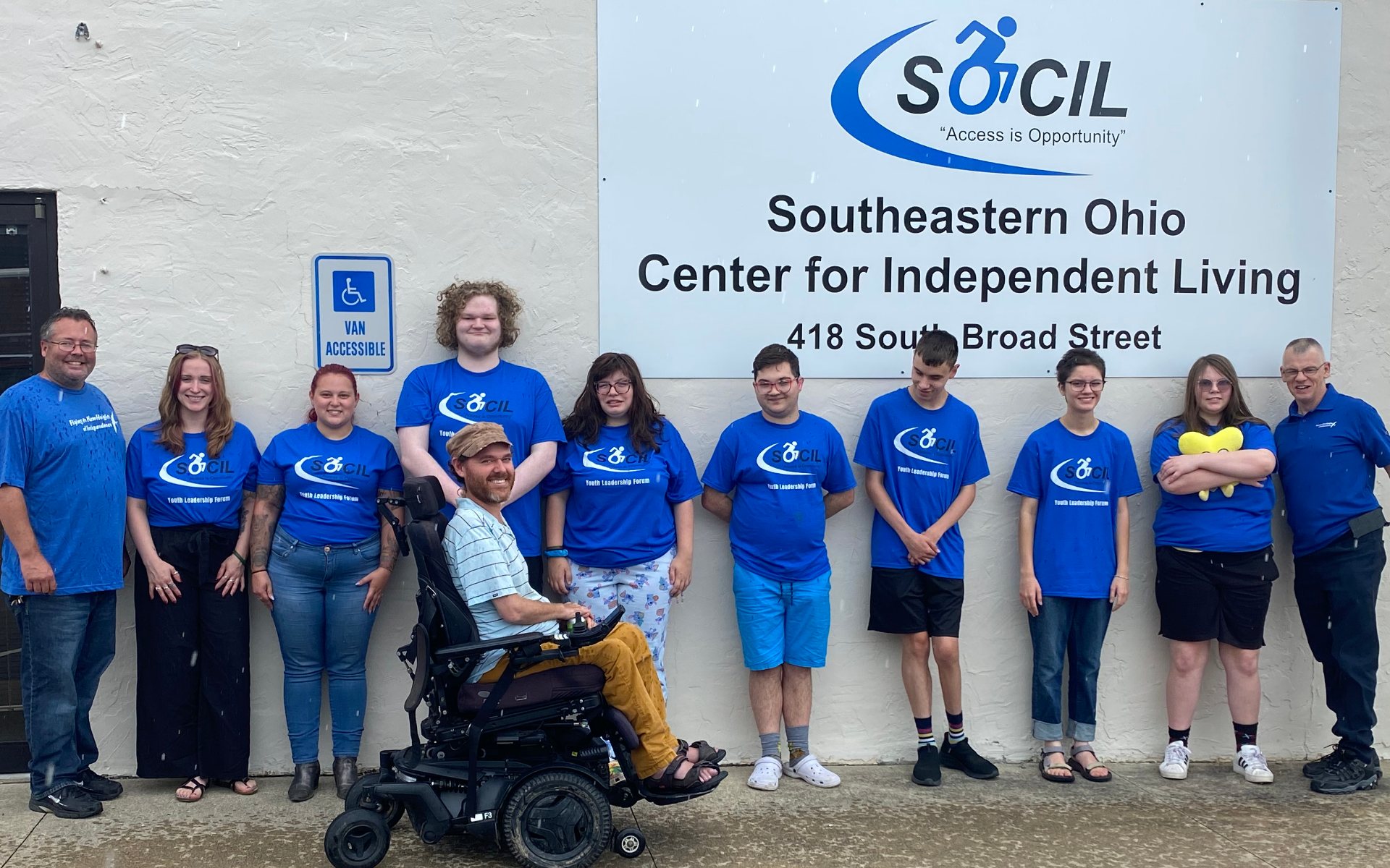SOCIL staff and Youth Leadership Forum participants in matching blue SOCIL shirts outside the SOCIL office in Lancaster