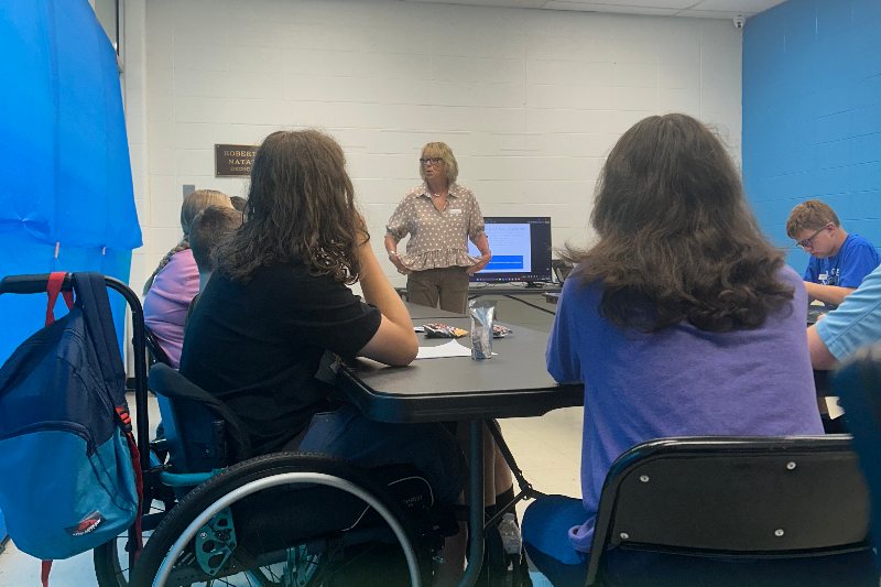 Students, including a wheelchair user, listen to a presenter during a training session